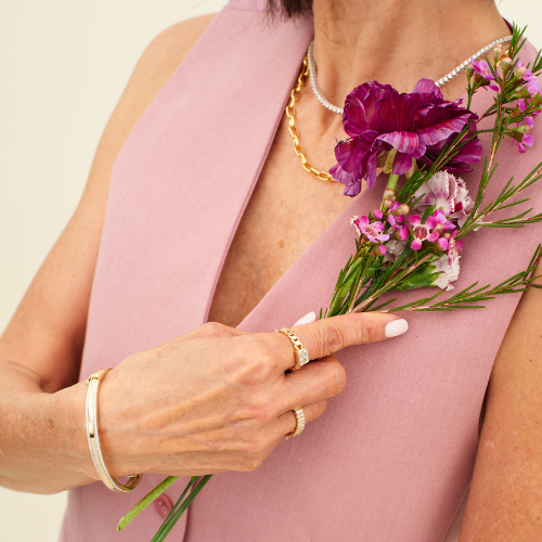 A mother wearing necklaces, bracelets, and rings as Mother's Day jewelry gifts. 