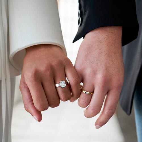 couple wearing diamond rings holding hands