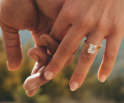 Model wearing gold diamond engagement ring.