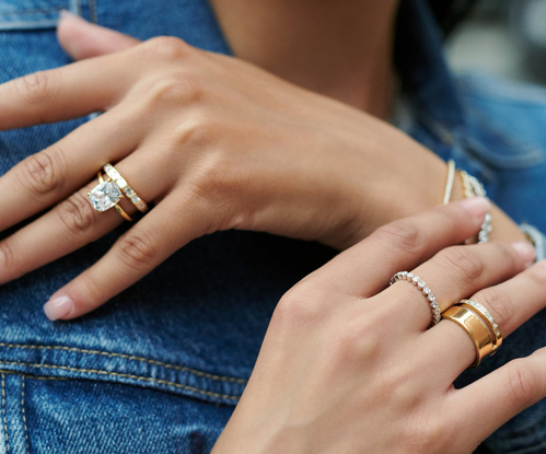 Model wearing gold diamond engagement ring and wedding rings.