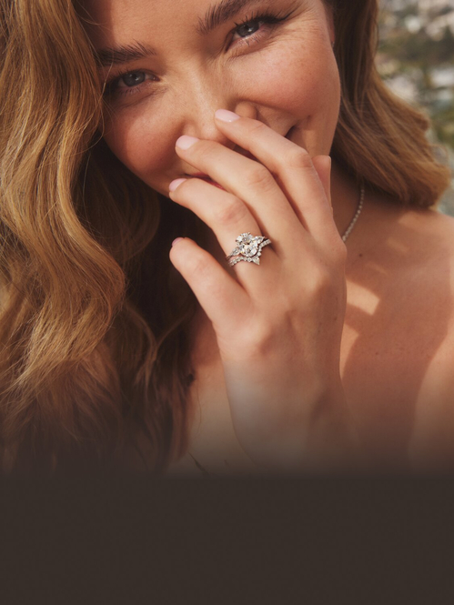 Model wearing three stone diamond engagement ring and contoured wedding ring.