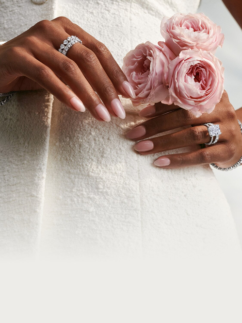 Model wearing diamond engagement ring, wedding bands and tennis bracelet.