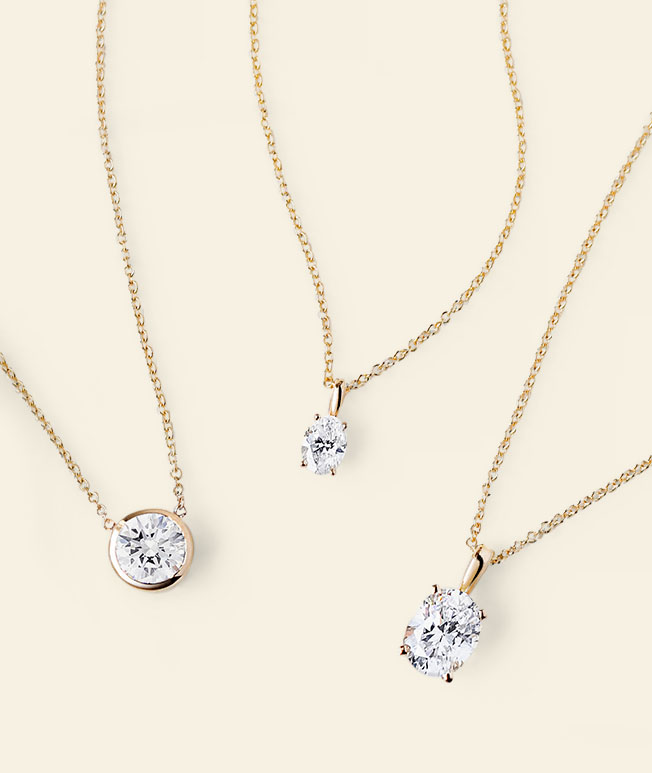 Assortment of yellow gold, round and oval diamond solitaire necklaces in a variety of settings.