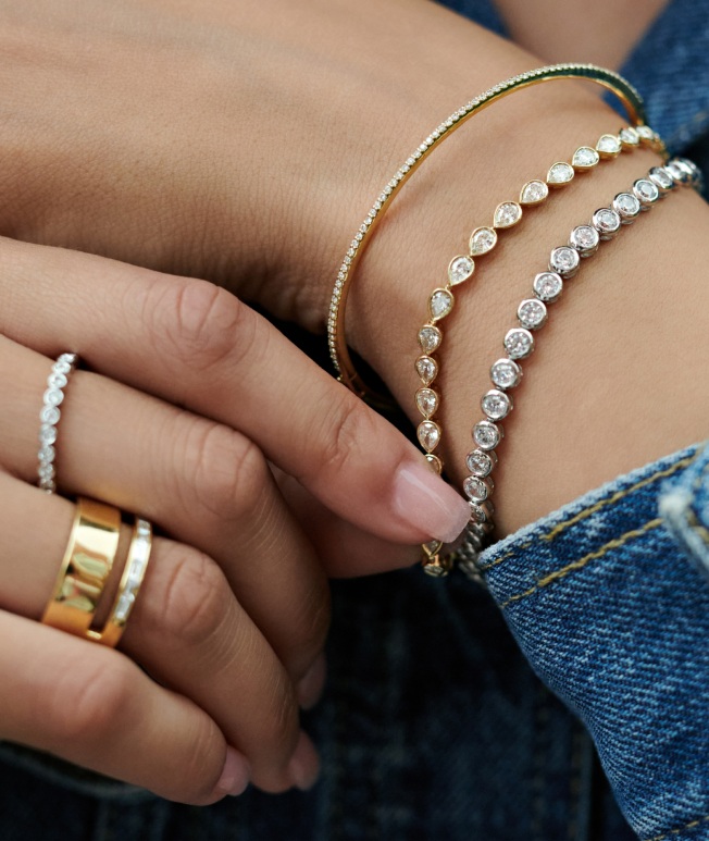 Model wearing bezel bracelets and fashion rings.