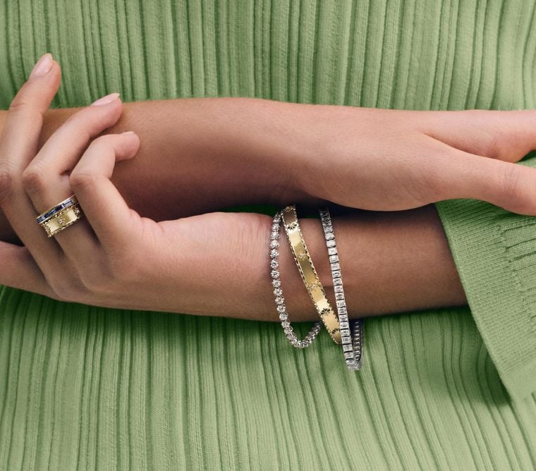Model wearing diamond tennis bracelets and bangle bracelet.
