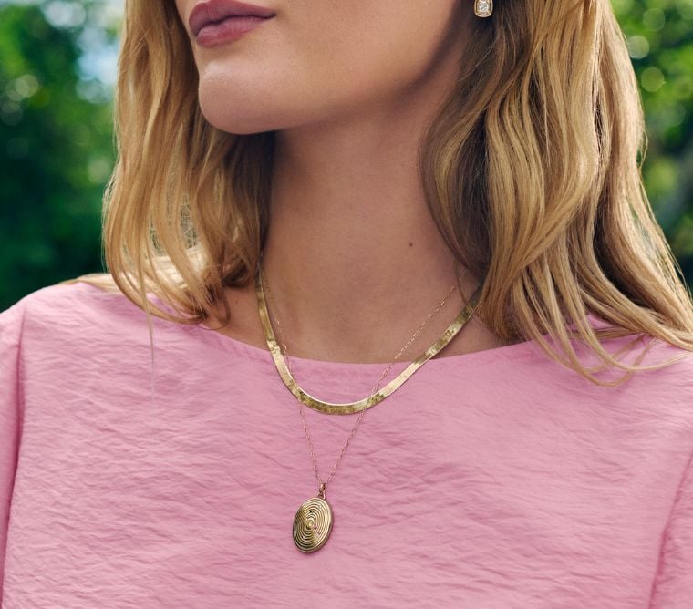 Model wearing a yellow gold chain and locket pendant.