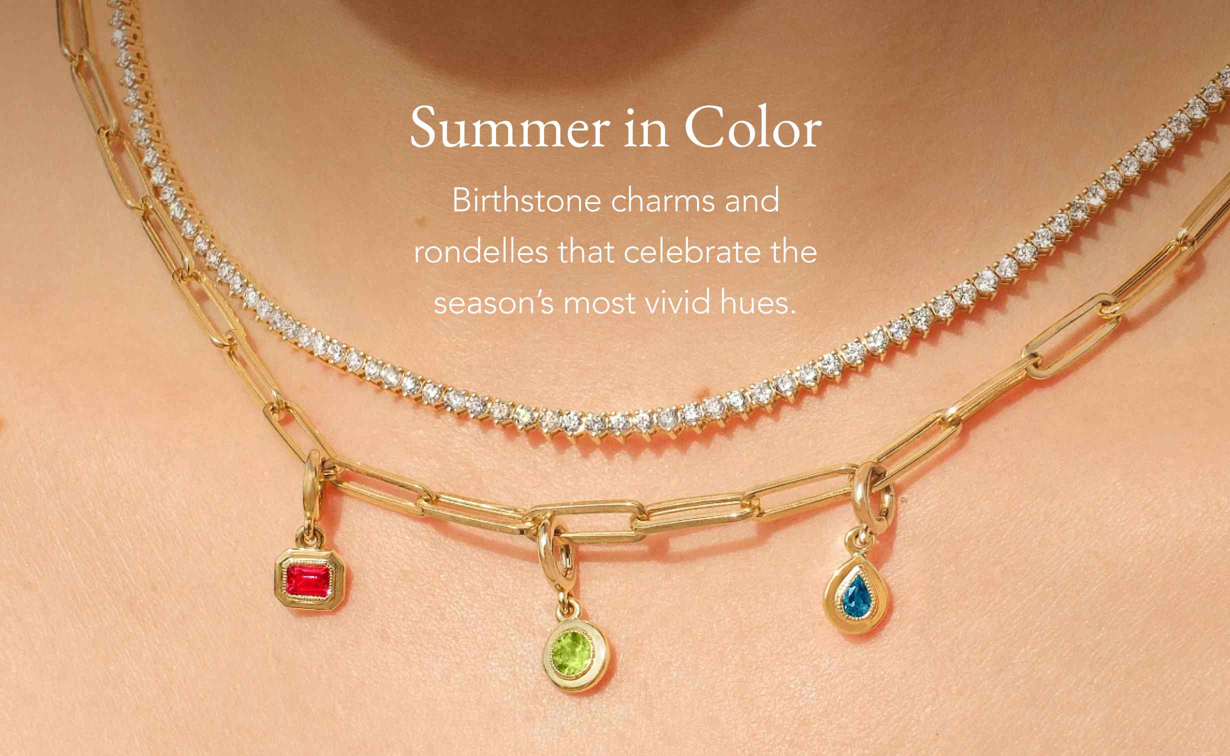 Person wearing a gold charm necklace with gemstone charms and a tennis necklace.