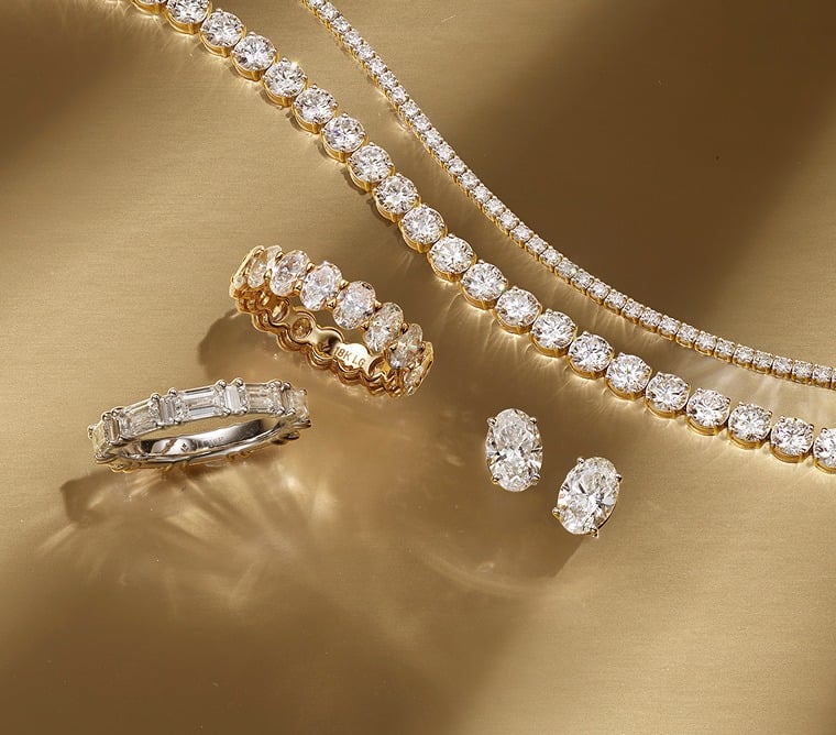 Assortment of diamond tennis bracelets, wedding ring, and oval stud earrings.