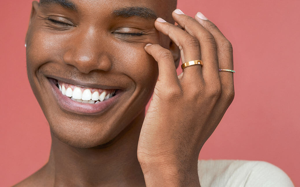 man smiling wearing lustrous gold rings